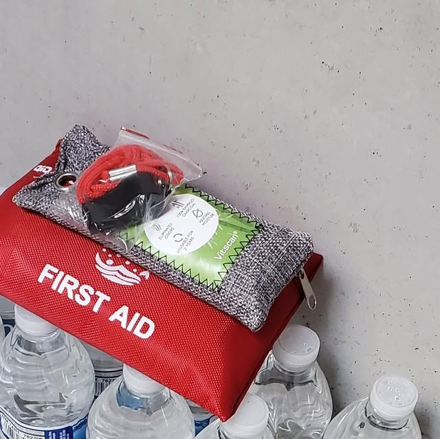Shelter Ready first aid kit with whistle on top of stocked water bottles