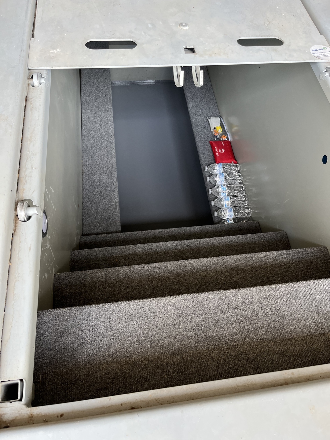 Carpeted storm shelter stairs with stocked supplies
