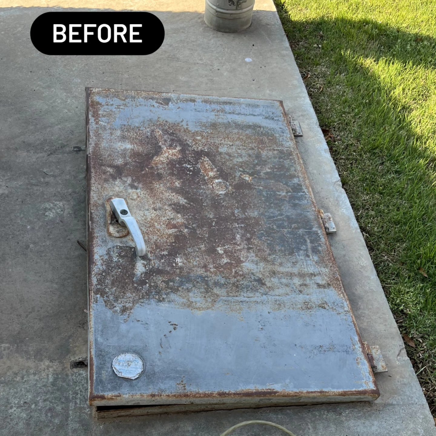 Storm shelter door before restoration — heavily rusted and peeling